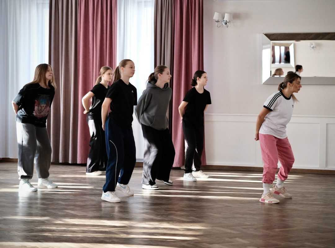 Zajęcia taneczne na&nbsp;sali: uczestnicy Dance Camp ćwiczą pod&nbsp;okiem instruktorki